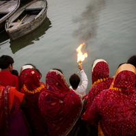 Ceremonial fire on the Ganges river. 
With Women dressed in red Sarees.
Varanasi, India.
Photo: Andrew Adams
