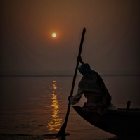 An Indian Man wearing a turban takes a Sunset boat ride on the River Ganges
