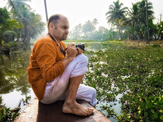 Andrew Adams taking a photo from a boat on the Kerala Backwaters.