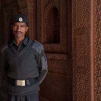 An Indian man wearing a grey uniform stands in a doorway at the Red fort in Delhi,India.  Photo: Andrew Adamsa