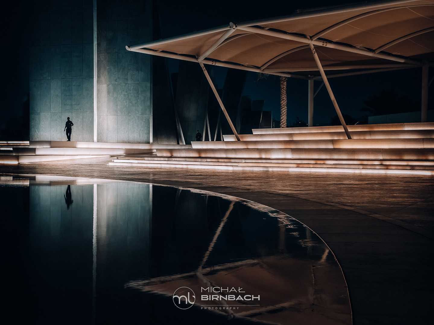 A man walking near the Wahat Al Karama monument in Abu Dhabi. Travel photography. Street photography. Orange & teal