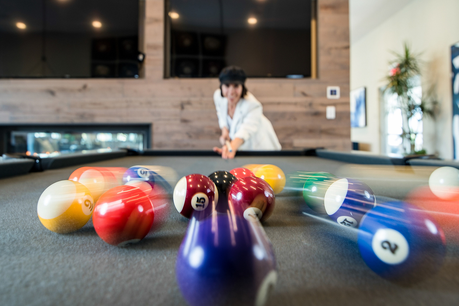 Woman playing pool with motion blurred balls using rear curtain sync.