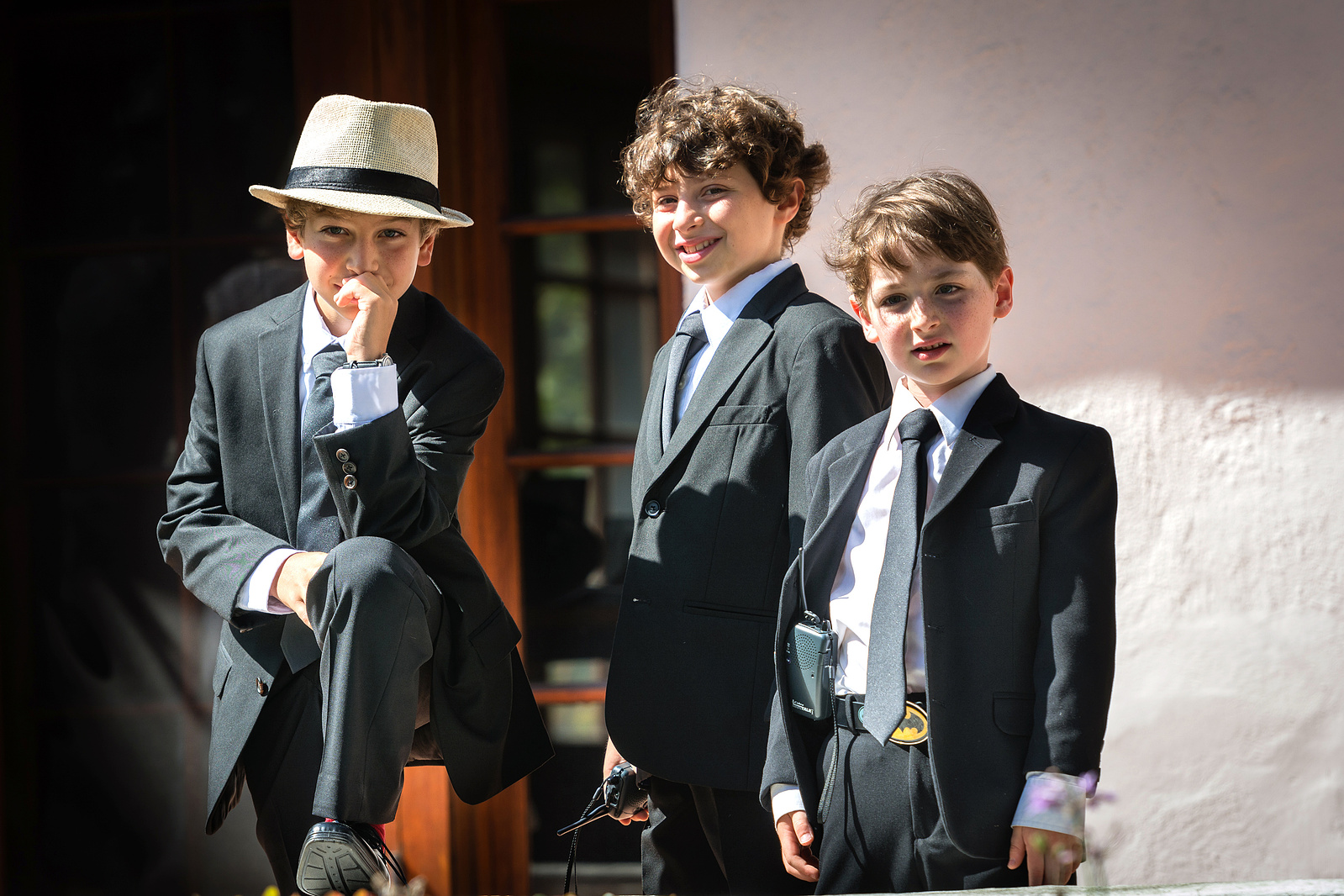 Three young boys pose for photo wearing suits.