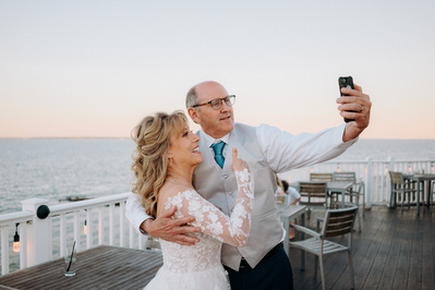 Bride giving thumbs up while taking selfie with groom at Cape Cod reception.