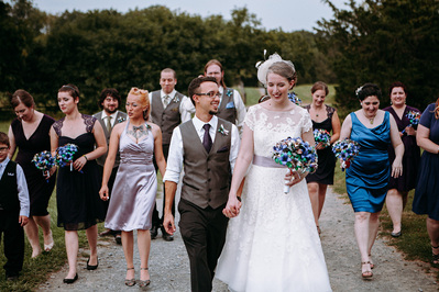 Wedding party and guests walking up gravel road.