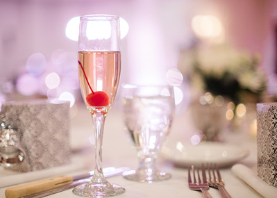 Cherry in champagne in pink light at wedding reception with bokeh.