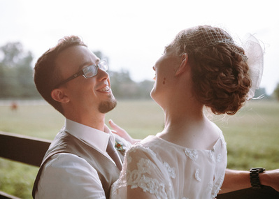 Bride and groom smiling in glow of golden hour portrait session.