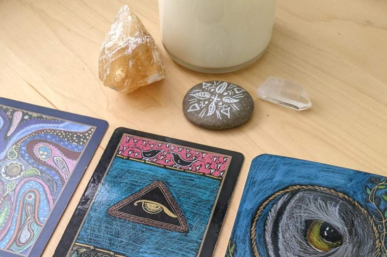 Three cards from the shamanic healing oracle, the Empathic Oracle and the Wild Elemental Oracle on a table with a crystal