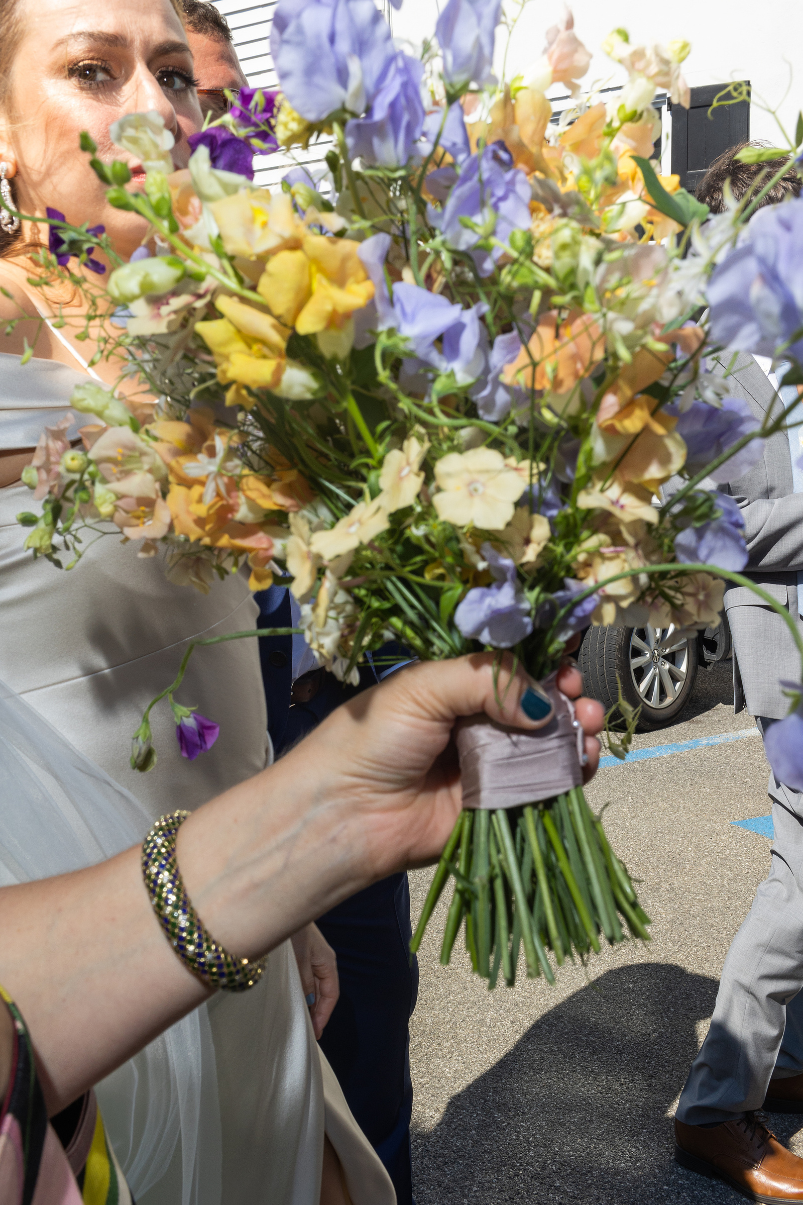 Flowers in front of bride partially covering her face. Wedding photojournalism at Senate Garage in Kingston, NY.