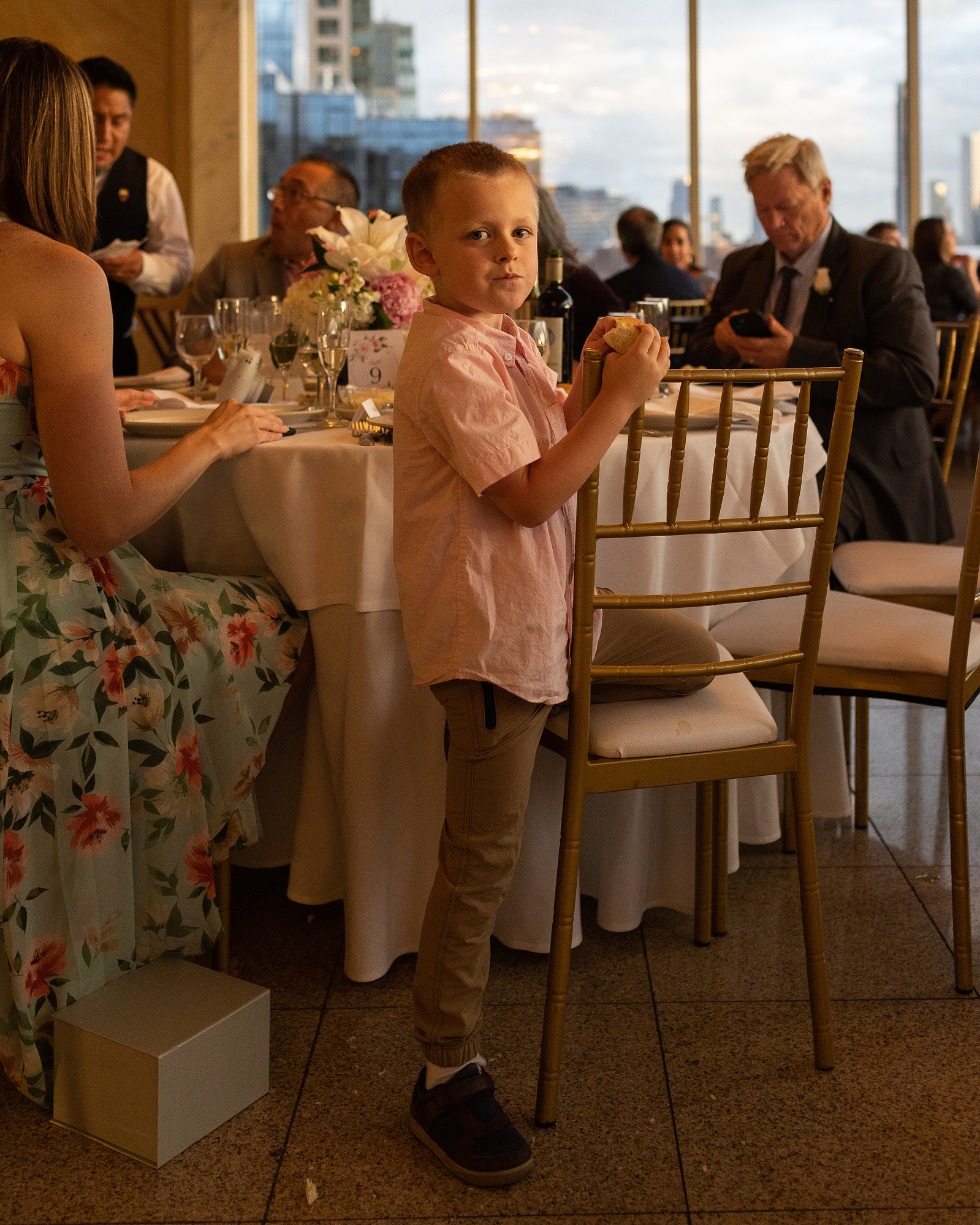 Young child stands at table. Wedding photojournalism at Giando on the Water in Brooklyn, NY. 