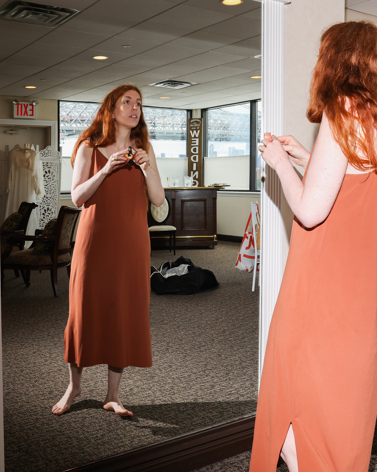 Bride, not yet in gown, looks in the mirror. Wedding photojournalism at Giando on the Water in Brooklyn, NY. 