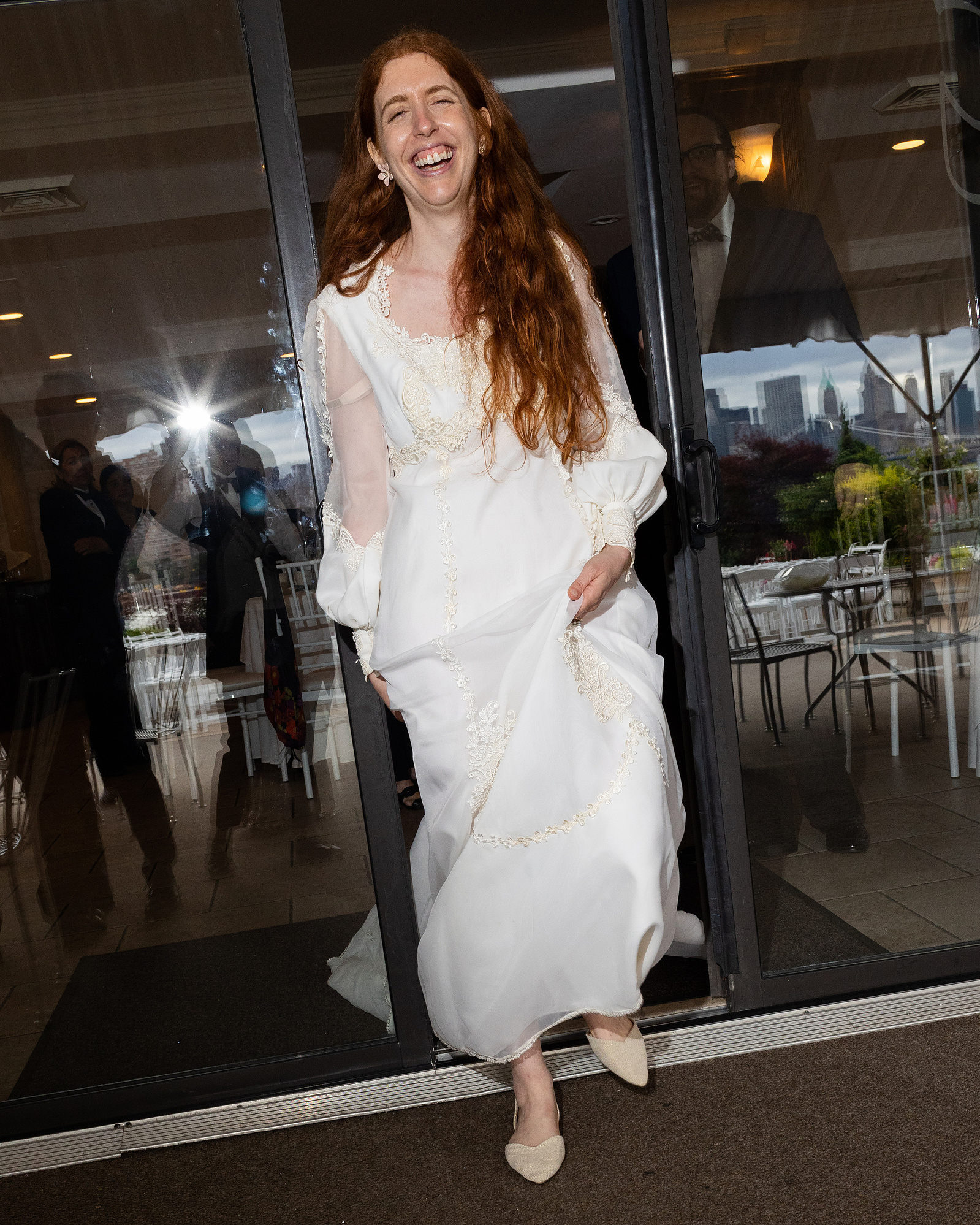Bride walks out glass doors at venue. Wedding photojournalism at Giando on the Water in Brooklyn, NY. 