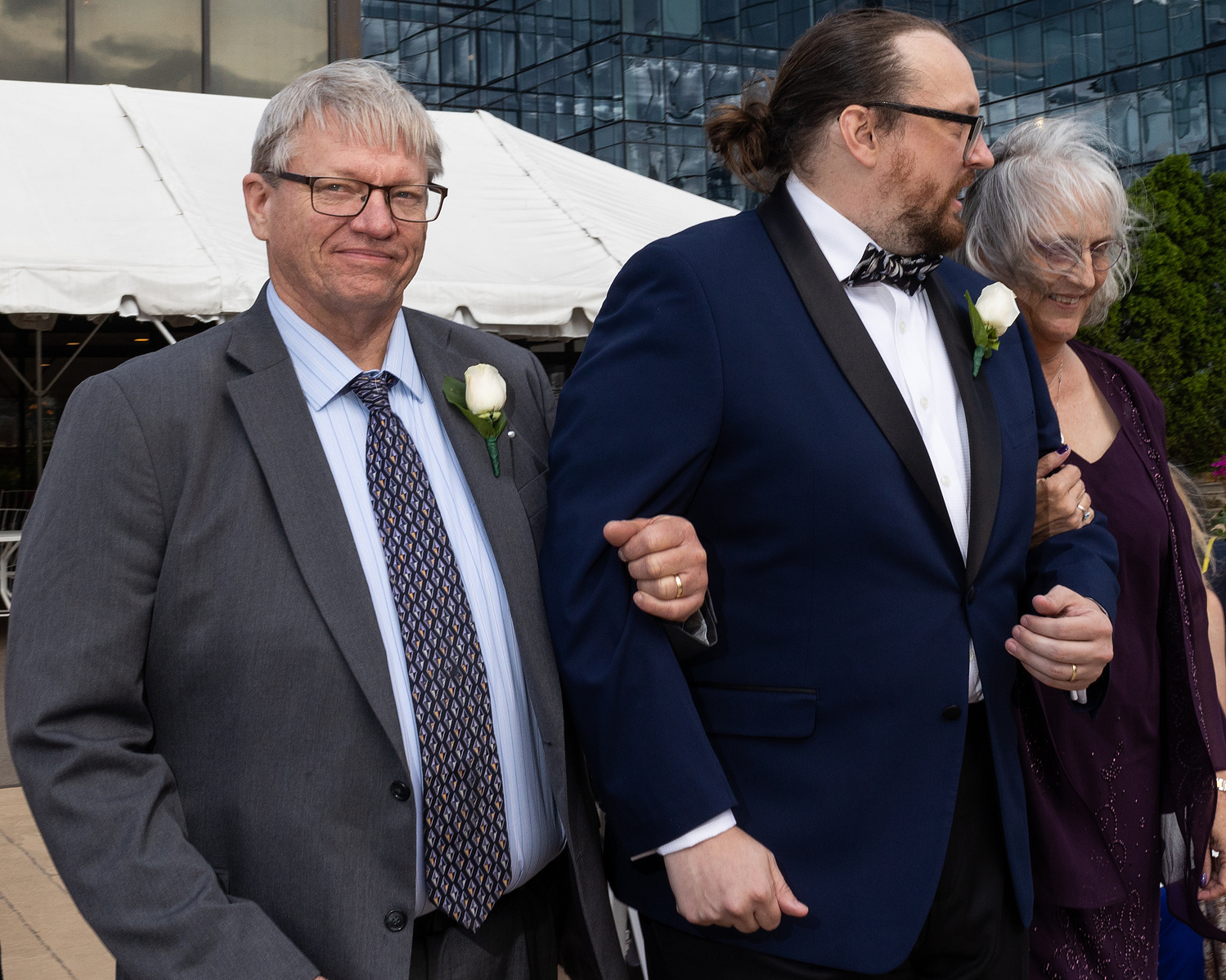 Father of the groom, groom and mother of the groom walk down the aisle. Wedding photojournalism at Giando on the Water in Brooklyn, NY. 