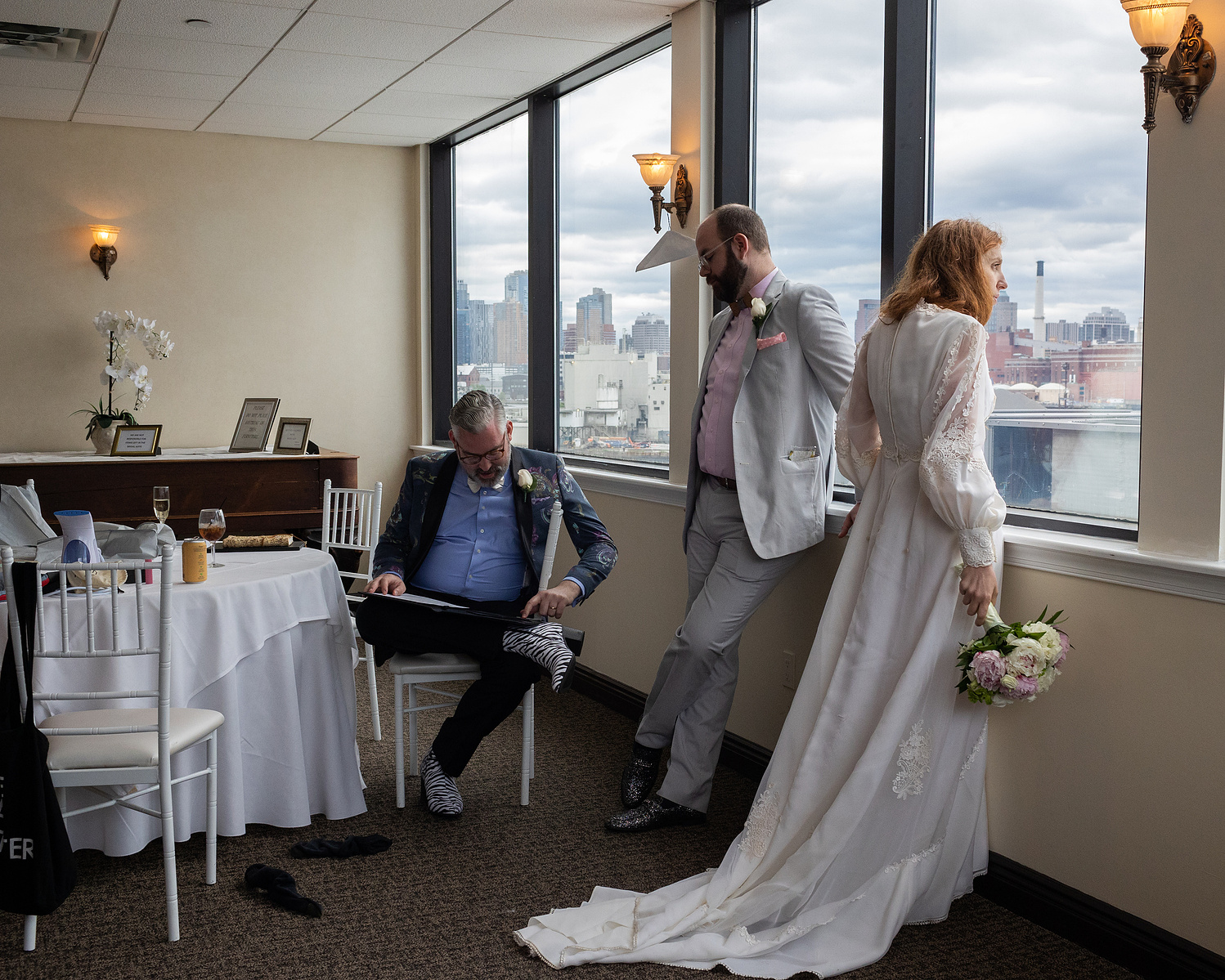 Bride looking out the window with her two friends sitting by her. Wedding photojournalism at Giando on the Water in Brooklyn, NY. 