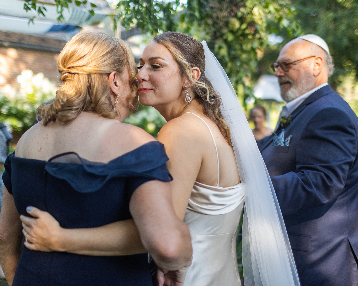 Bride and mother kiss on cheek. Wedding photojournalism at Senate Garage in Kingston, NY.