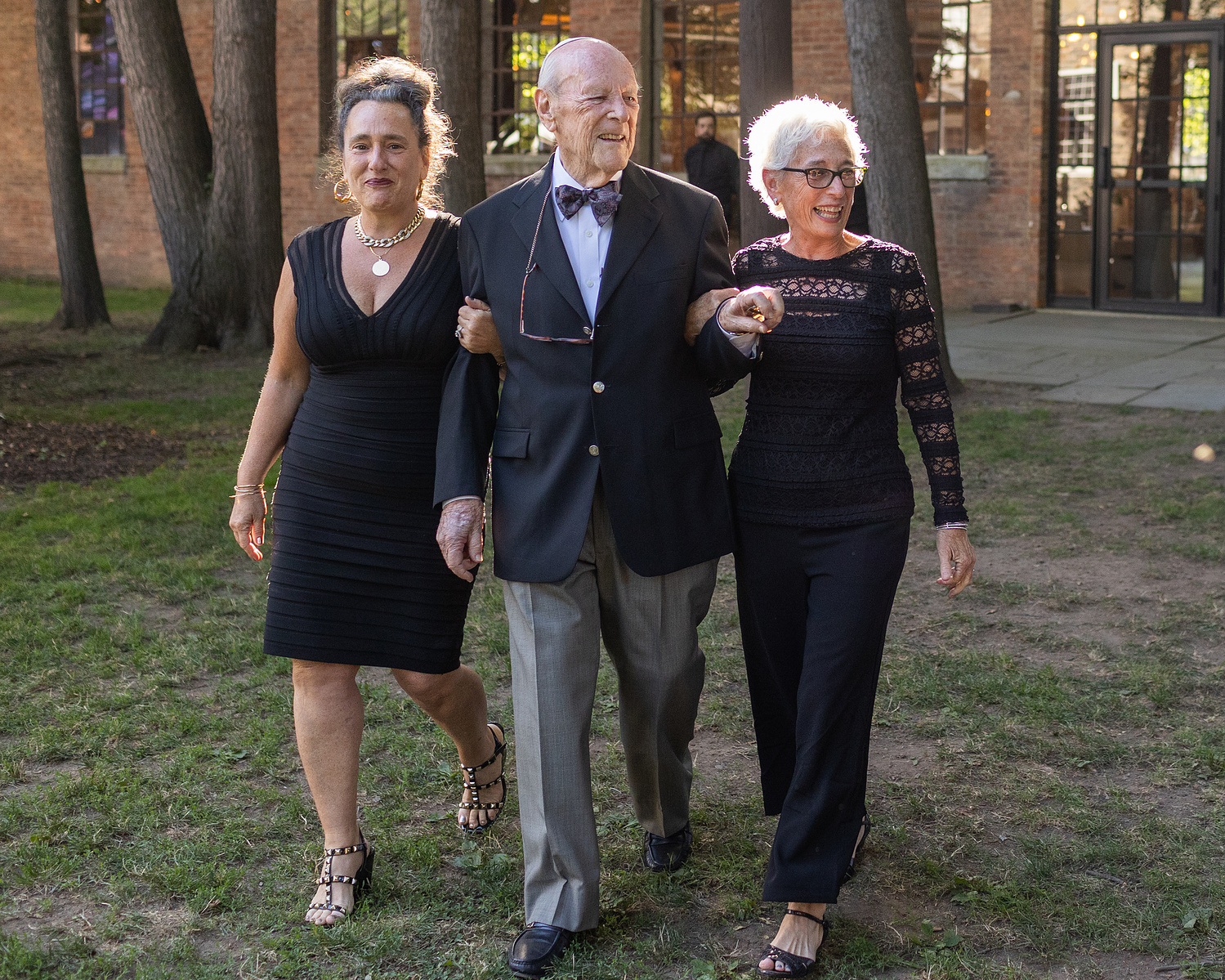 Grandfather of bride walks into ceremony with his two daughters. Wedding photojournalism at Senate Garage in Kingston, NY.
