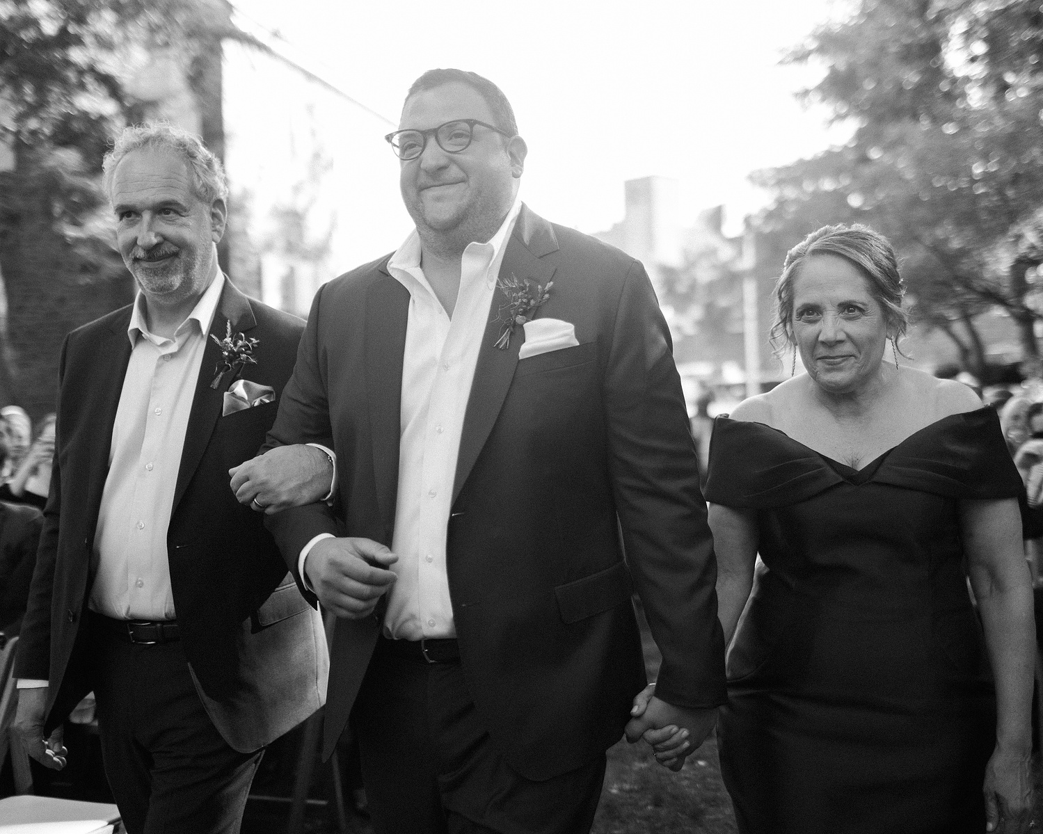 Groom is escorted down aisle by his father and mother. Wedding photojournalism at Senate Garage in Kingston, NY.