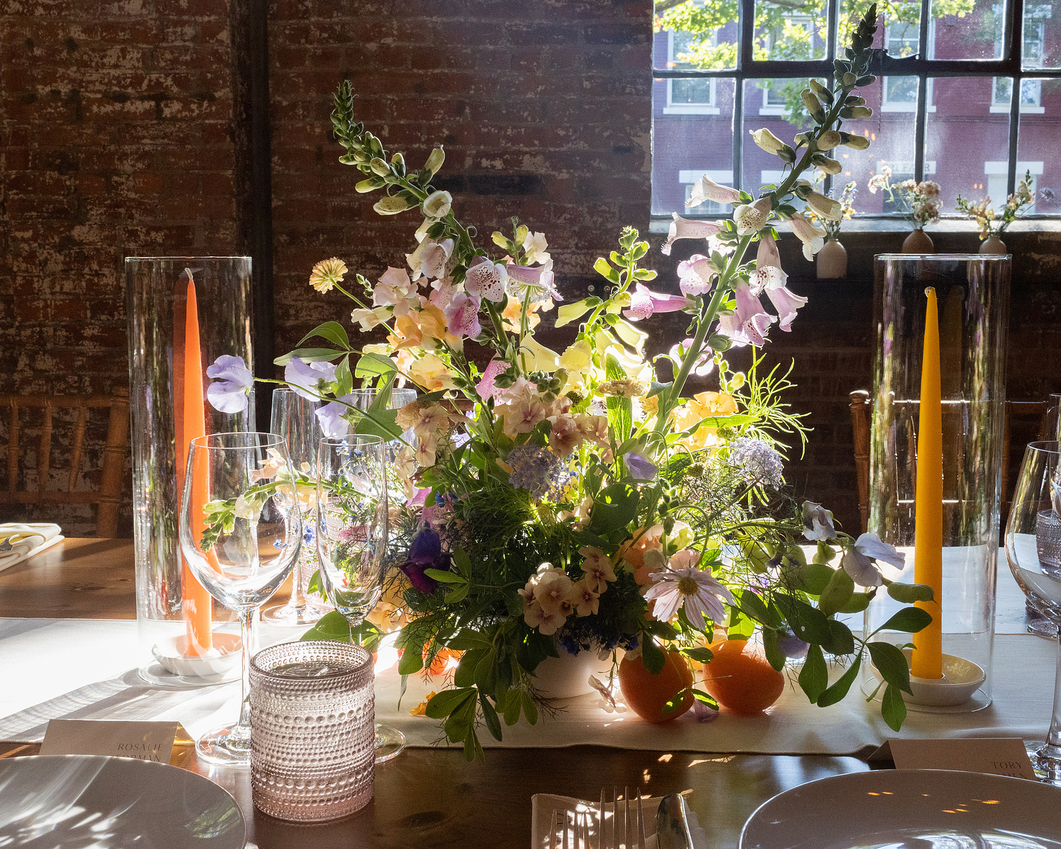 Flower arrangement and candles on table in golden light at beginning of reception. Wedding photojournalism at Senate Garage in Kingston, NY.