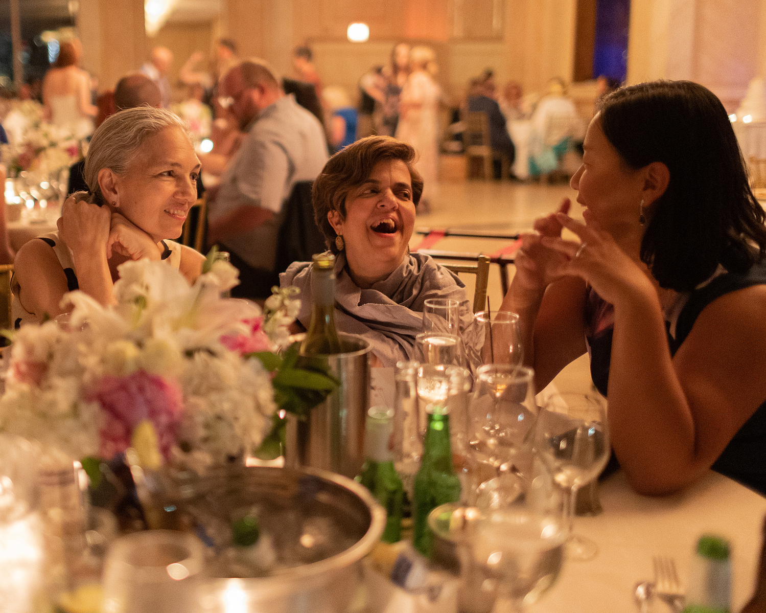 Wedding guests at table, laughing. Wedding photojournalism at Giando on the Water in Brooklyn, NY. 