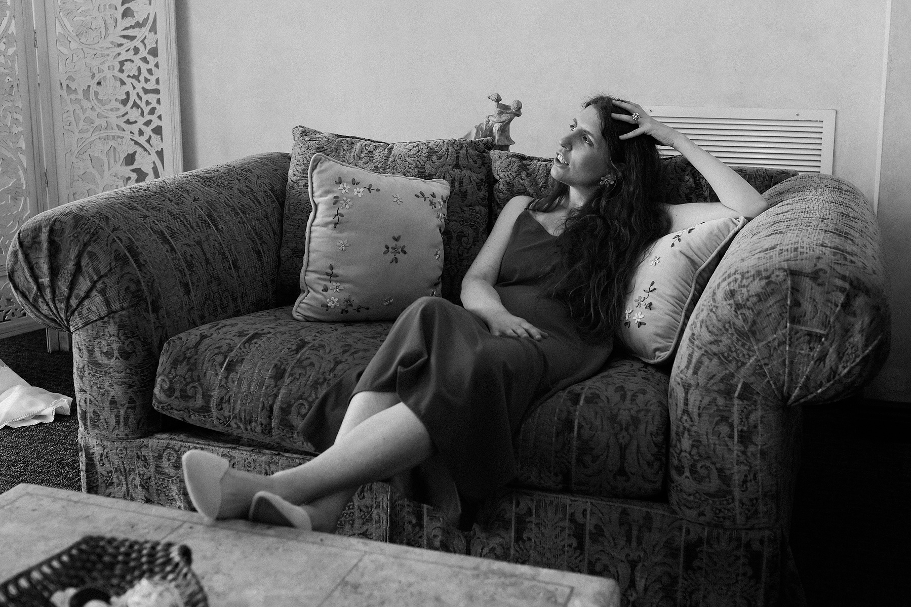 Wedding photojournalism at Giando on the Water in Brooklyn, NY. Black and white image where bride is sitting on couch. 