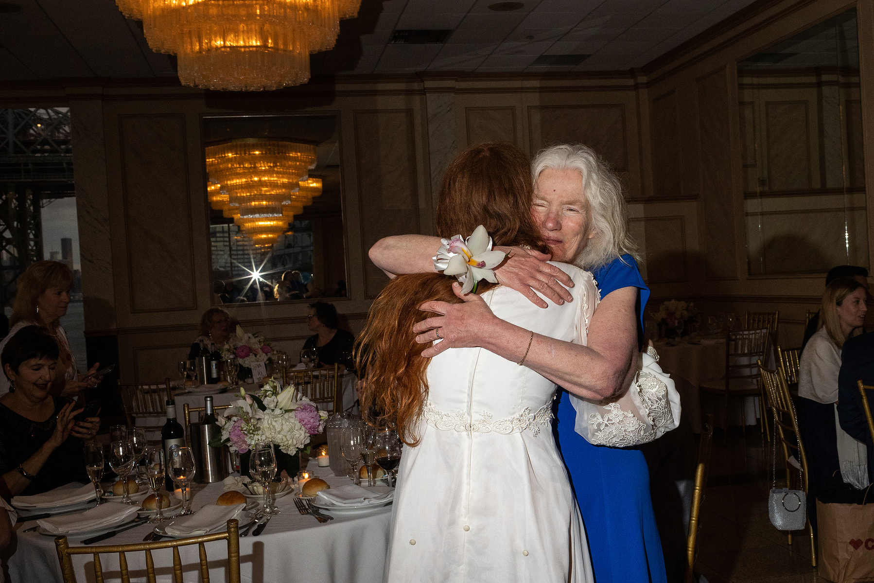 Bride and mother embrace at reception inside. Wedding photojournalism at Giando on the Water in Brooklyn, NY. 