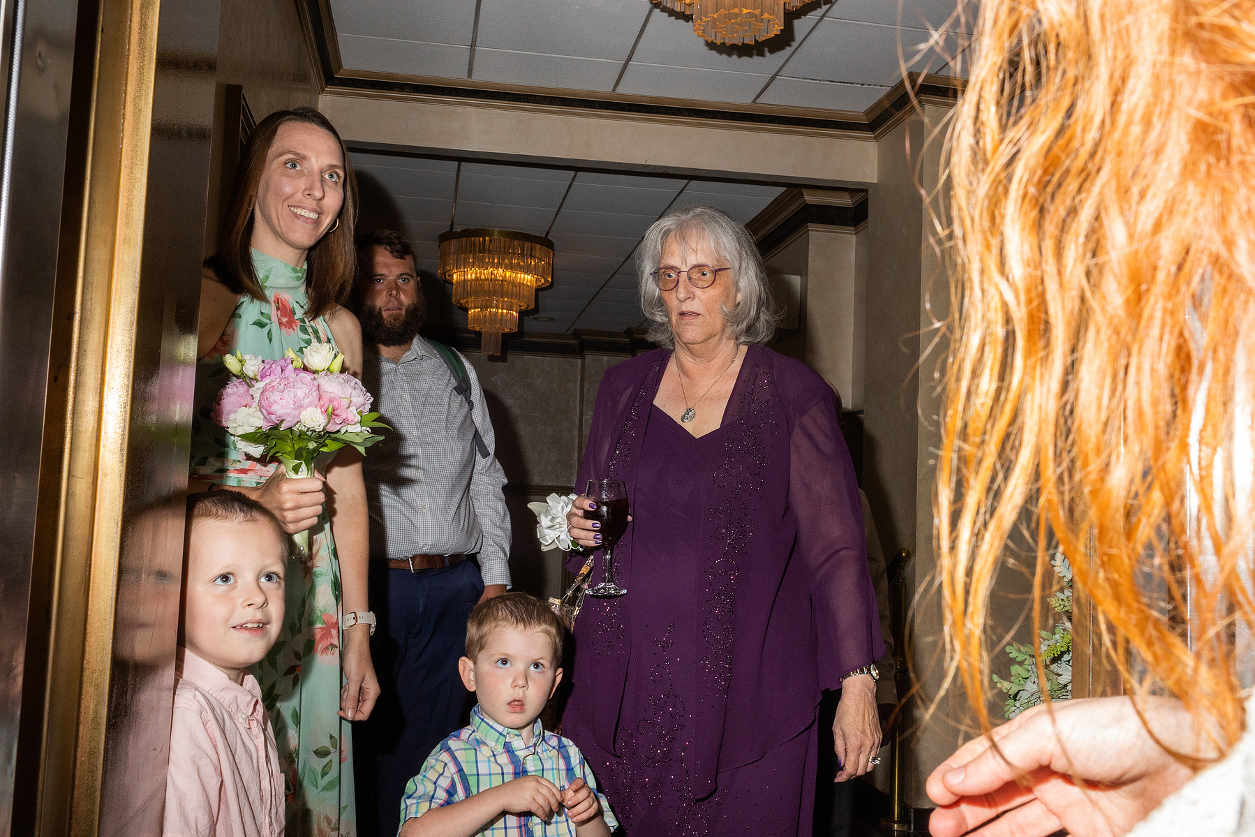 Family sees bride for first time when the elevator stops on their floor. Wedding photojournalism at Giando on the Water in Brooklyn, NY. 