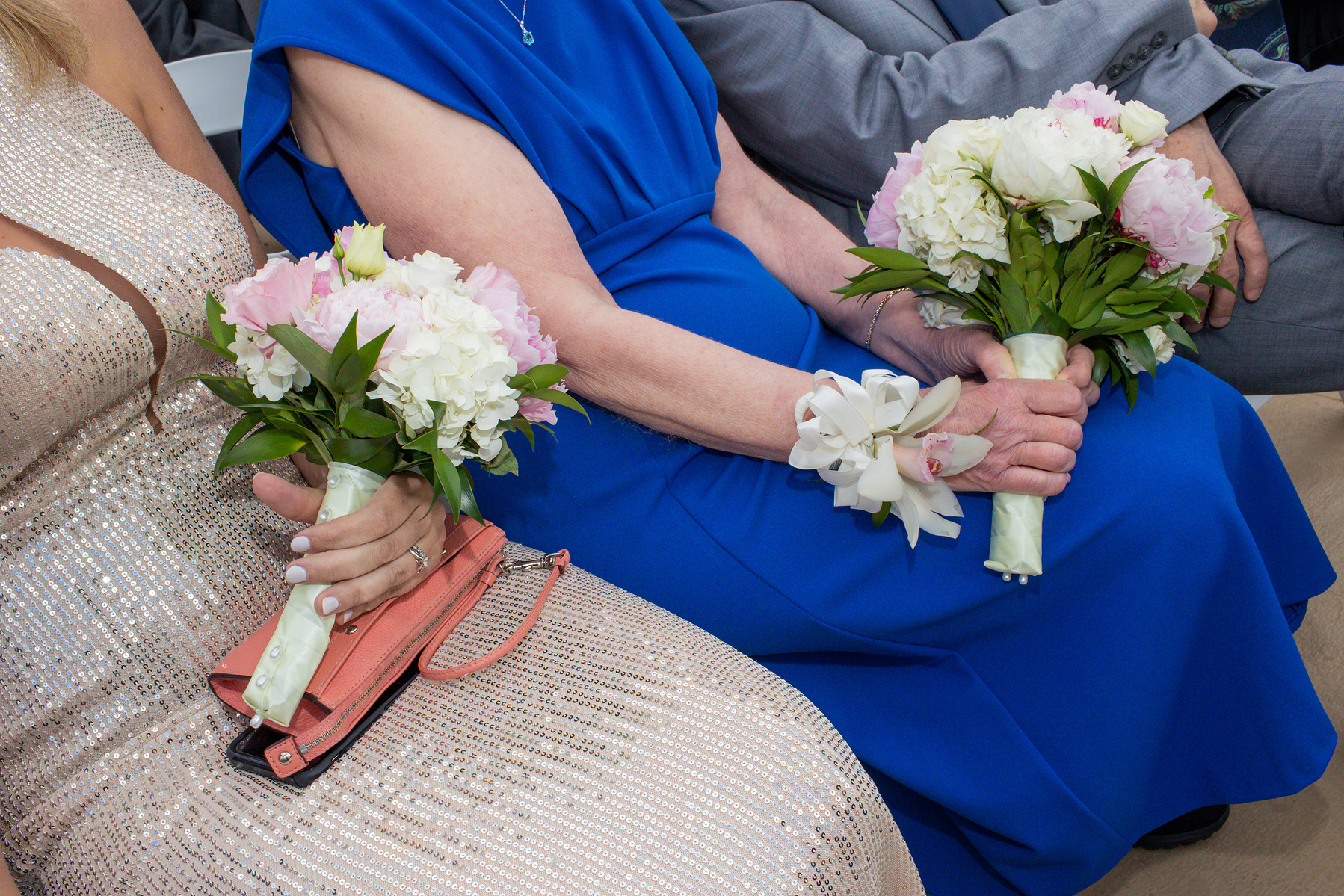 Two members of wedding party hold bouquets while sitting. Wedding photojournalism at Giando on the Water in Brooklyn, NY. 