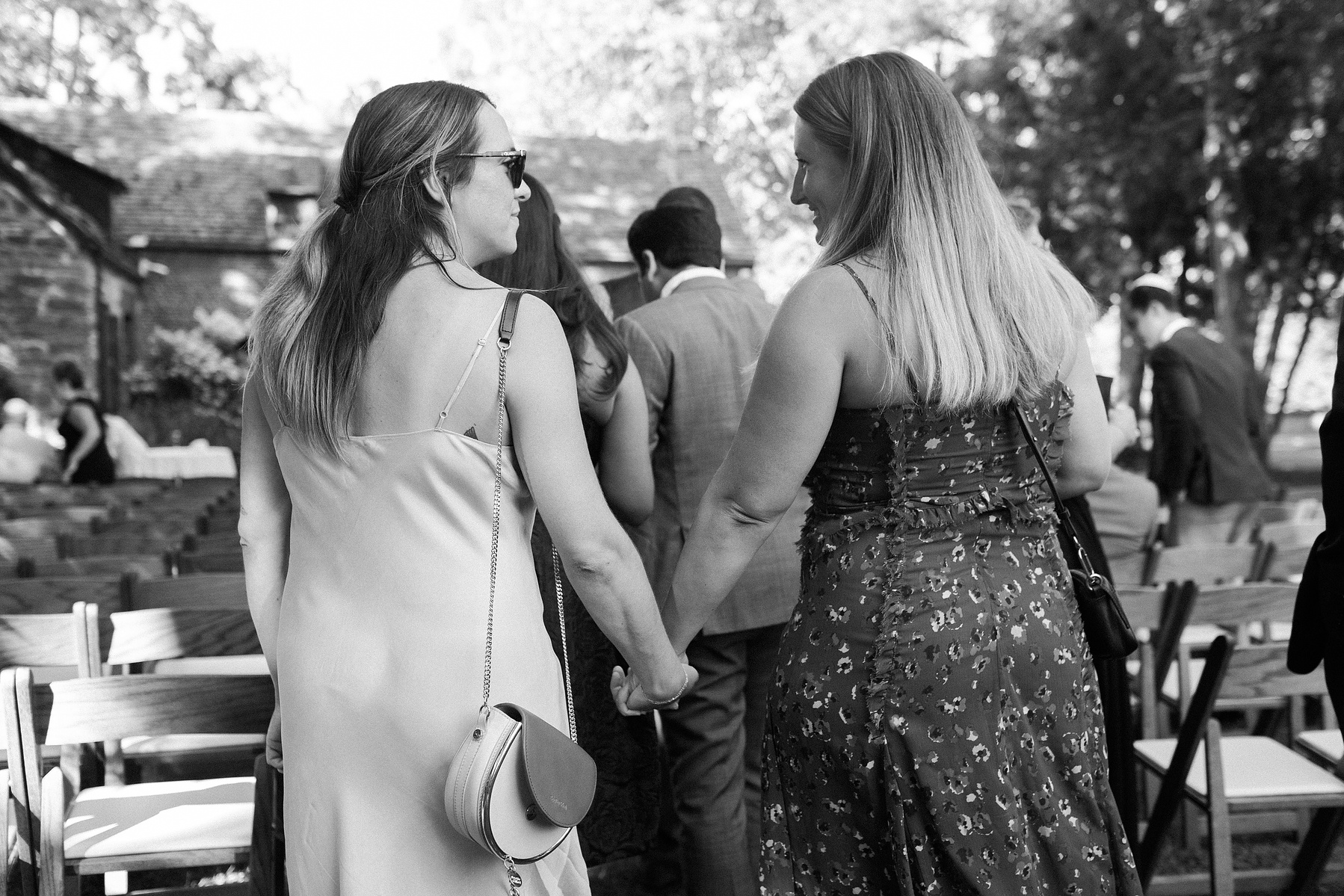 Wedding guests enter ceremony holding hands. Wedding photojournalism at Senate Garage in Kingston, NY.