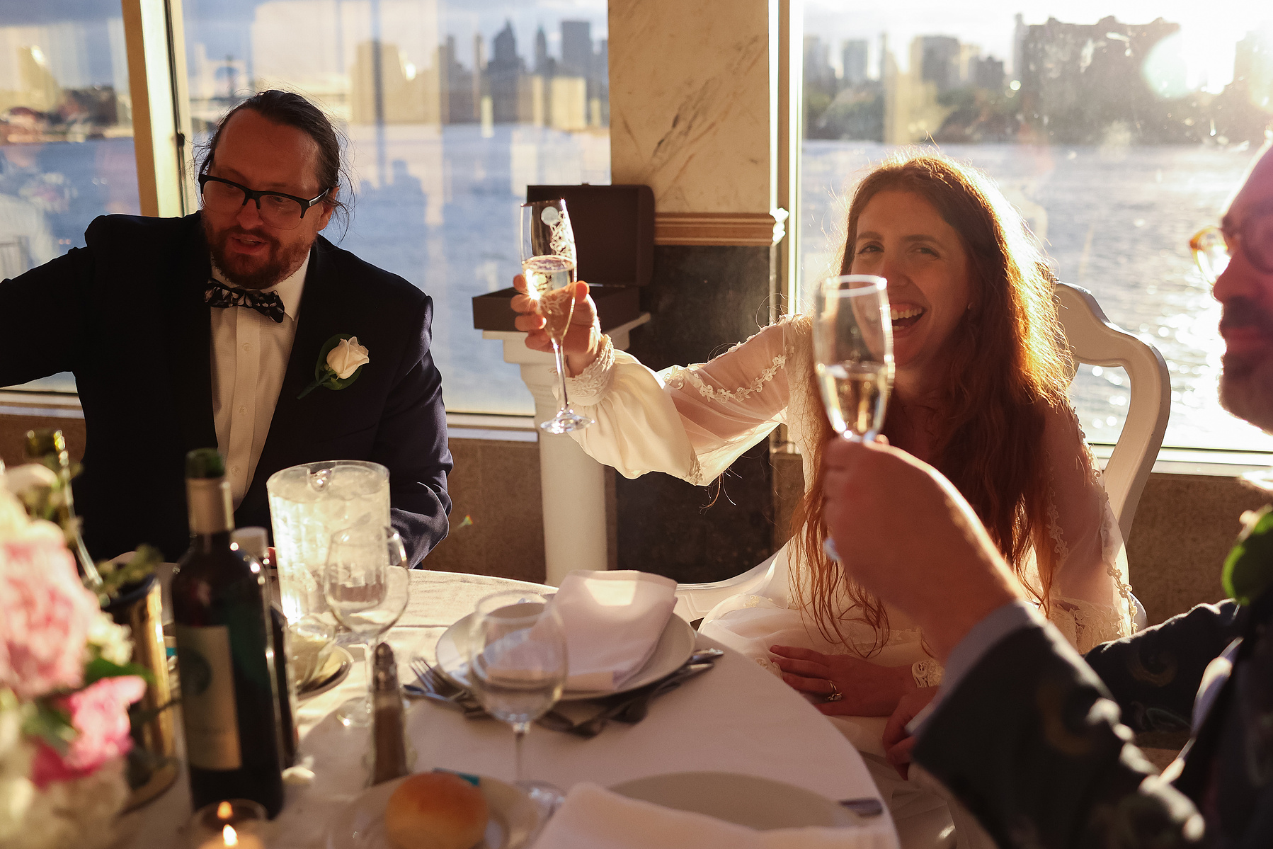 Groom and Bride raise glass for toast in warm light of setting sun. Wedding photojournalism at Giando on the Water in Brooklyn, NY. 