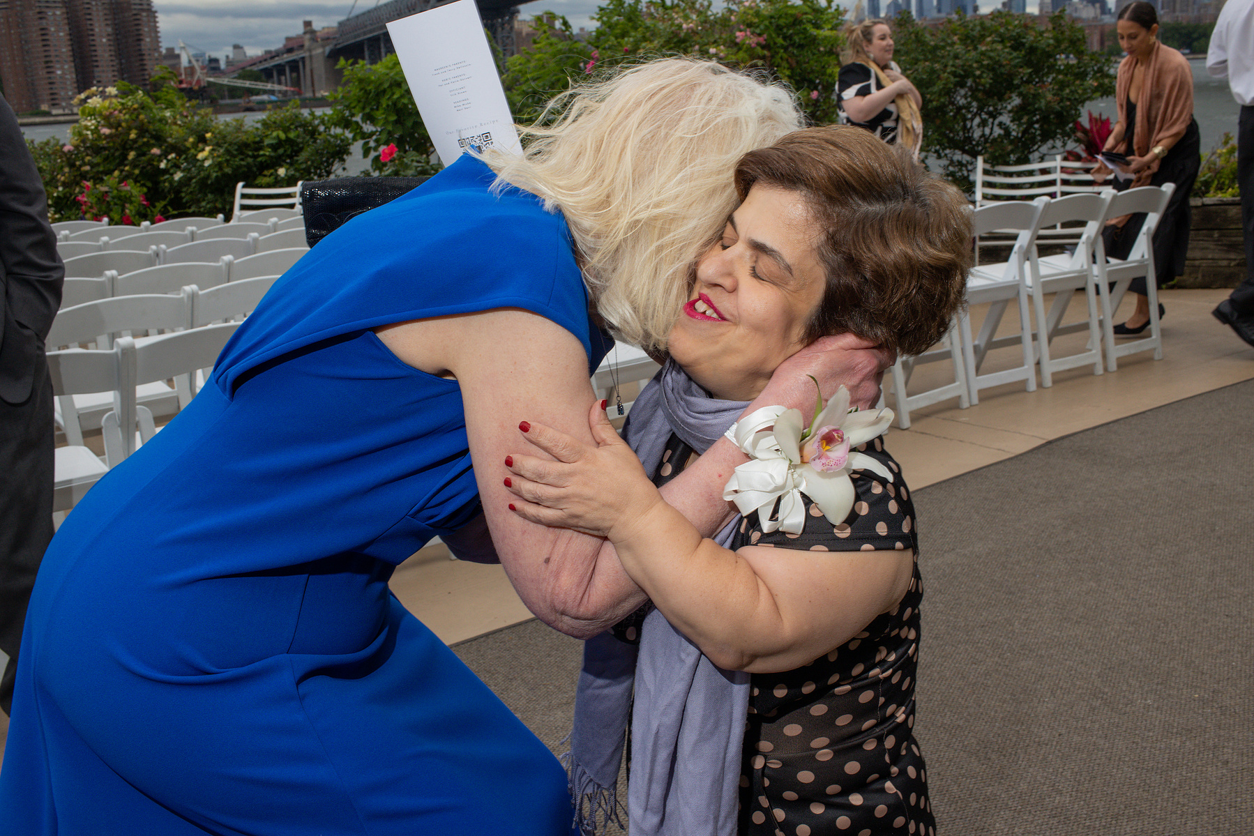 Mother of the bride hugs wedding guest. Wedding photojournalism at Giando on the Water in Brooklyn, NY. 
