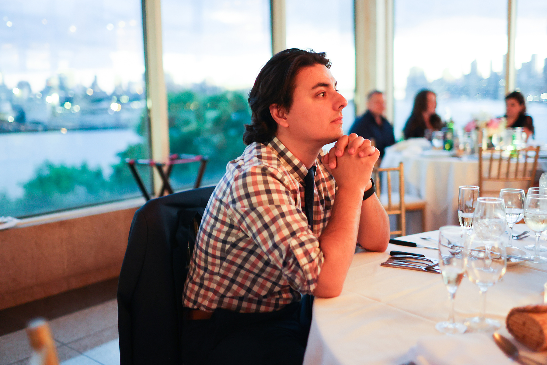 Wedding guest sits at table in warm light. Wedding photojournalism at Giando on the Water in Brooklyn, NY. 