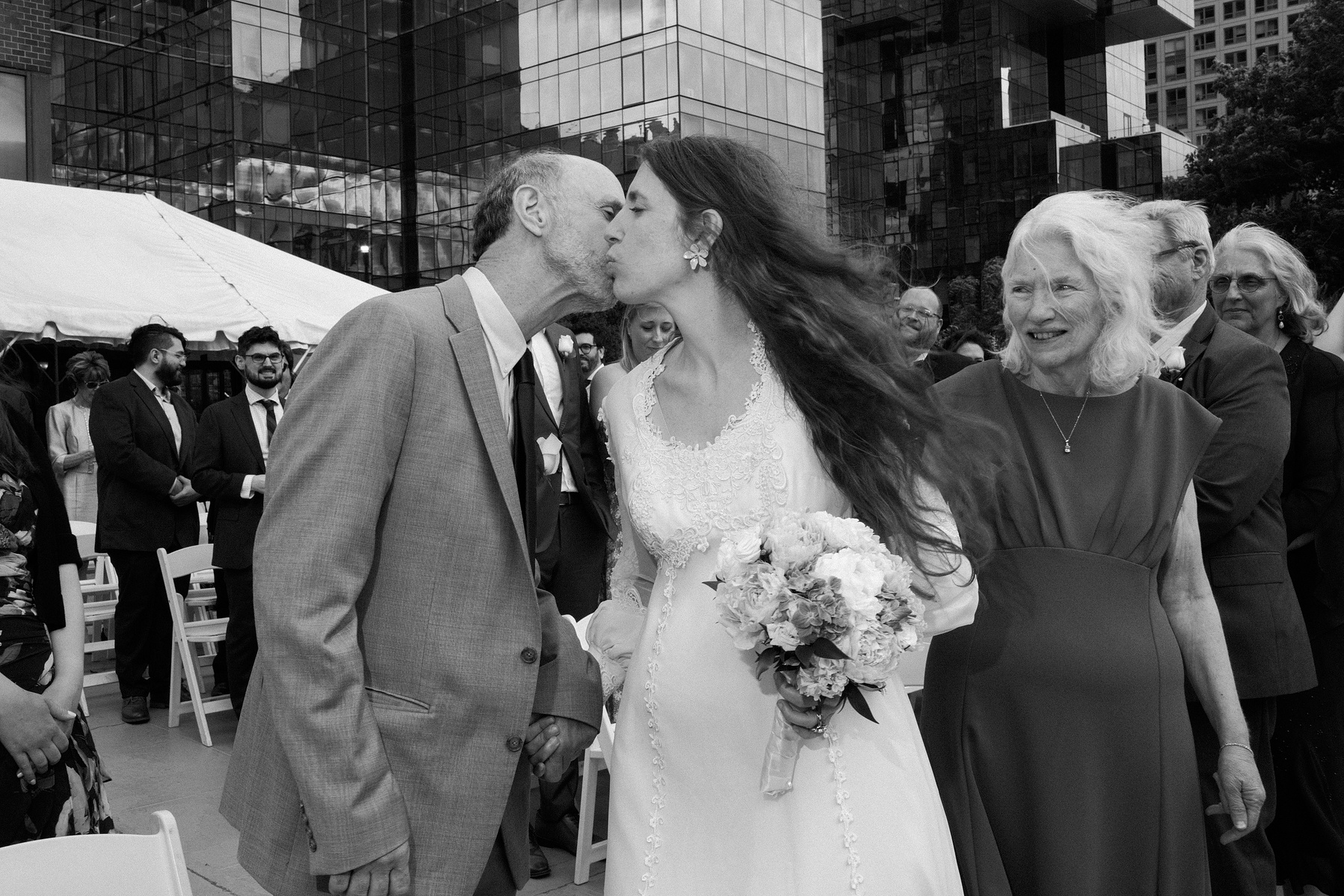 Bride and father kiss cheeks at end of the aisle. Wedding photojournalism at Giando on the Water in Brooklyn, NY. 