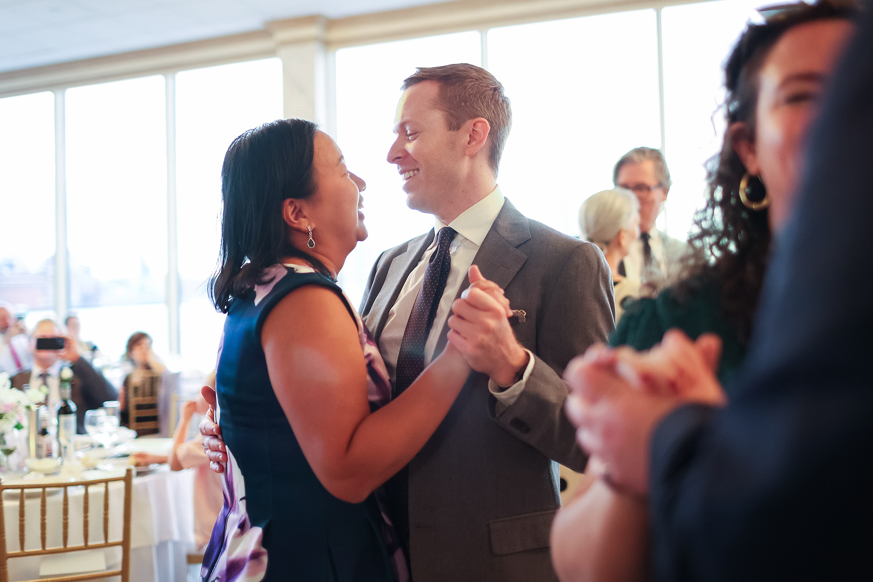 Wedding guests dance in warm light of setting sun. Wedding photojournalism at Giando on the Water in Brooklyn, NY. 