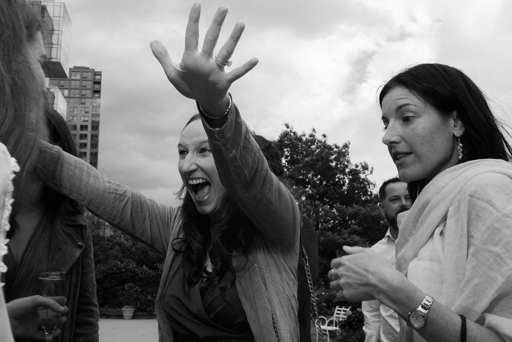 Wedding guest has arms up for hug. Wedding photojournalism at Giando on the Water in Brooklyn, NY. 