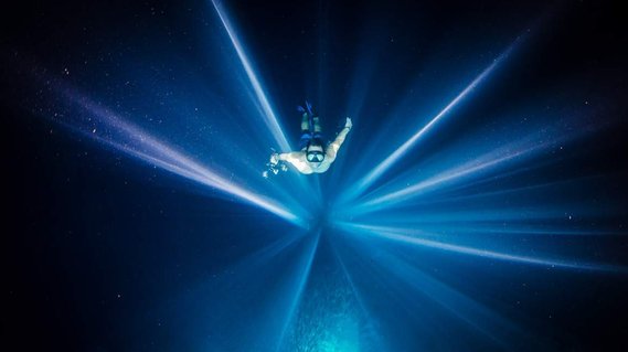 Taro Smith following rays of light to the surface in a cave in Vavau.  Photo by Shawn Heinrichs
