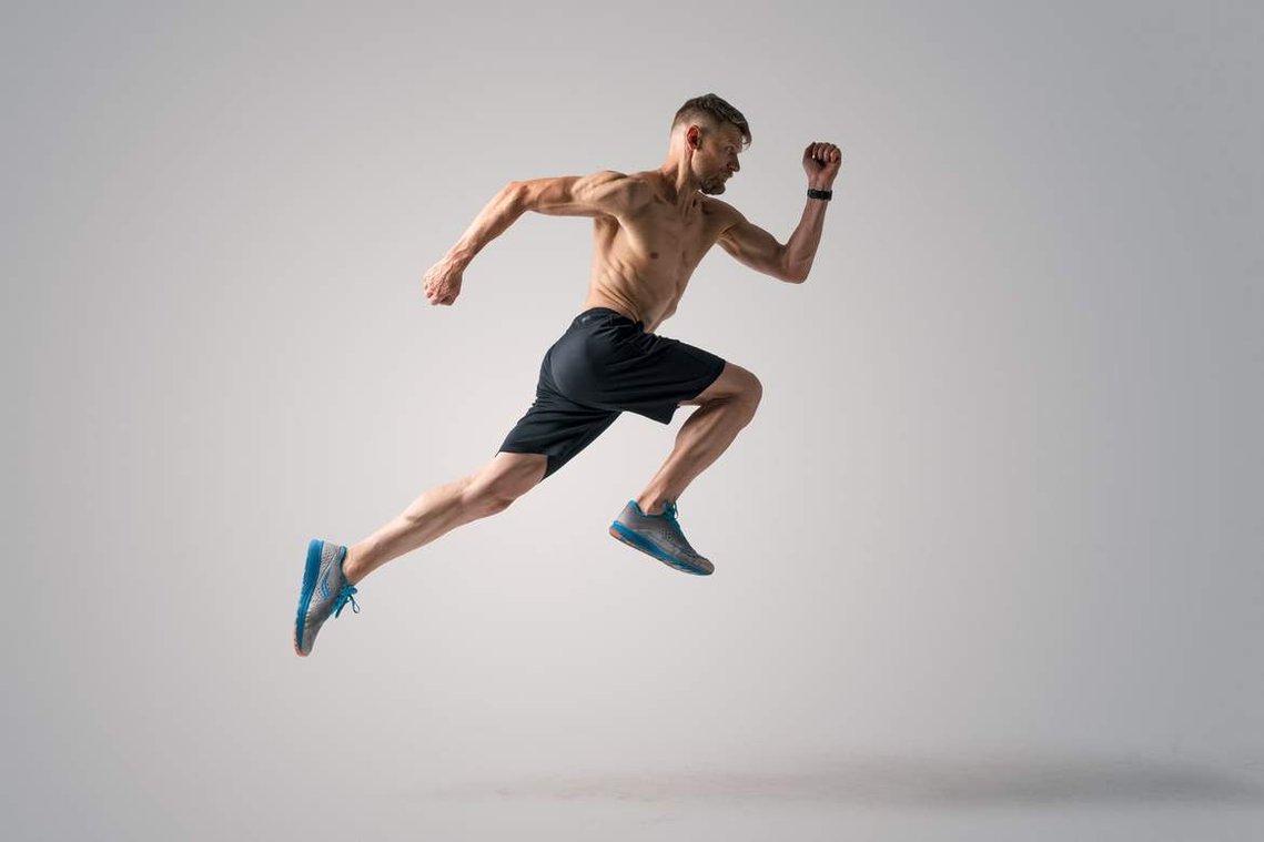 Muscular man running forward on a white background.