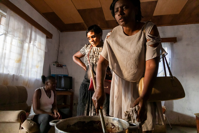 Cocoa powder and hot water are mixed together and put to boil. While Beatrice is mixing Mirelle in the background is paying attention to any noise produced by the boiling of the oil that is obtained during the cooking.