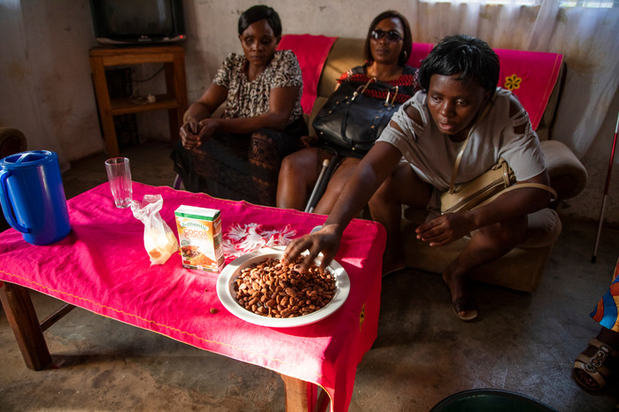 Beatrice, Mireille and Bernadette sitting in Eveline's living room during the workshop. They are invited by the training leader to touch, smell and taste the cocoa beans before starting the process.