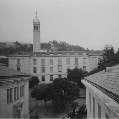 a landscape shot taken from a window on the second floor of Dwinelle at UC Berkeley. we see the campanile, Wheeler Hall, and the Berkeley hills in the distance. 