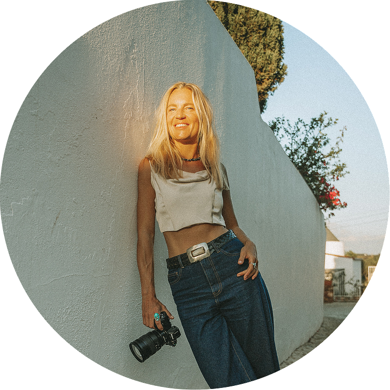 Photographer during a photo shooting standing in the sun in the Algarve, Portugal, with her camera in her hands.