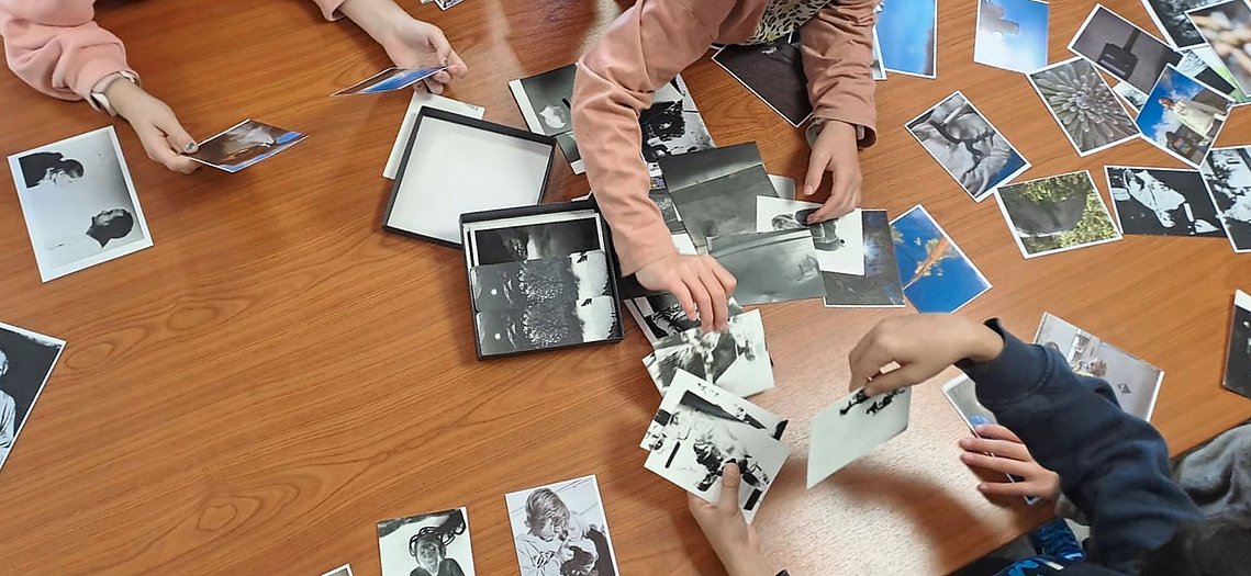 mains d'enfants triant des photographies pour préparer une restitution d'atelier photo sous forme d'exposition Luz Saint-Sauveur Pyrénées
