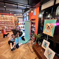Jonny Bosworth the London Dog Photographer taking photos in his pop up studio set up in Papersmiths for Chelsea Dog Day 2022.  the window display shows a portrait of Archie the Norfolk terrier by Woof Portraits. 