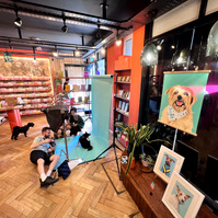 Jonny Bosworth the London Dog Photographer taking photos in his pop up studio set up in Papersmiths for Chelsea Dog Day 2022.  the window display shows a portrait of Archie the Norfolk terrier by Woof Portraits. 