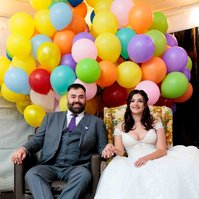 man and woman sitting in brown chair and floral chair in front of balloons inspired by the movie Up
