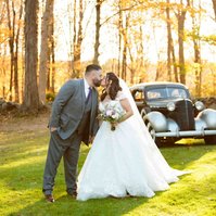 bride and groom kissing in front of old car
