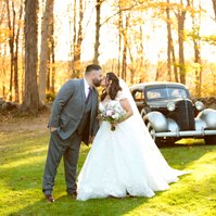 bride and groom kissing in front of old car