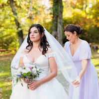bridesmaids in purple dress adjusting bride's veil