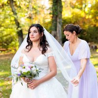 bridesmaids in purple dress adjusting bride's veil
