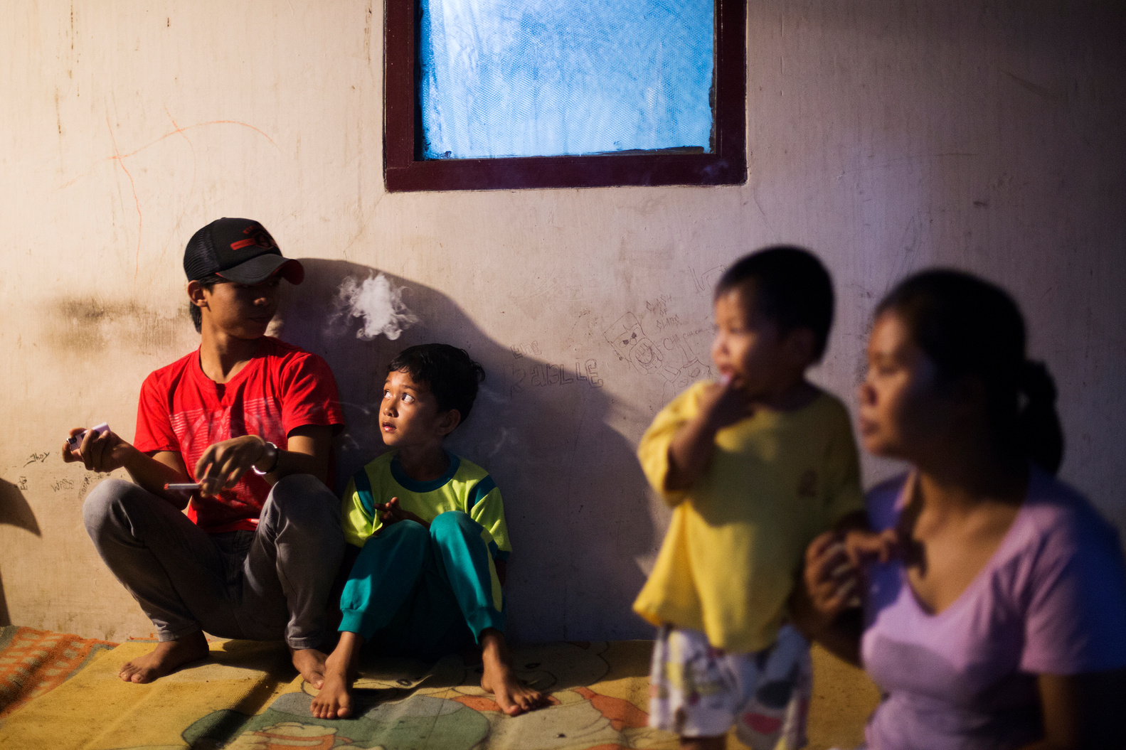 DEPOK, INDONESIA - Mar. 25, 2015: Jodi Hermawan, 15, who started smoking two years ago, smokes next to his neighbour and mother. His family is considered middle-class. His favourite cigarettes are Gudang Garam Filter.