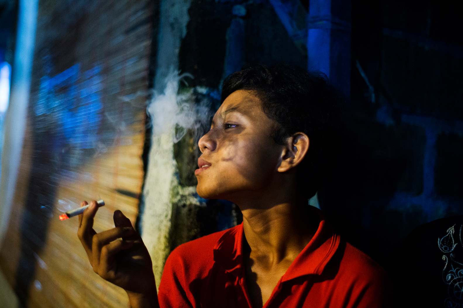Wawan, 15 years, who started smoking last year, has a cigarette on on March 27, 2015. His father smokes and he receives money from his parents for cigarettes. (Photo By: Michelle Siu)